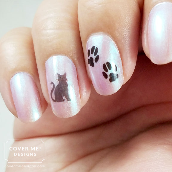 gray cat and black paw print nail art decals on pink nail polish